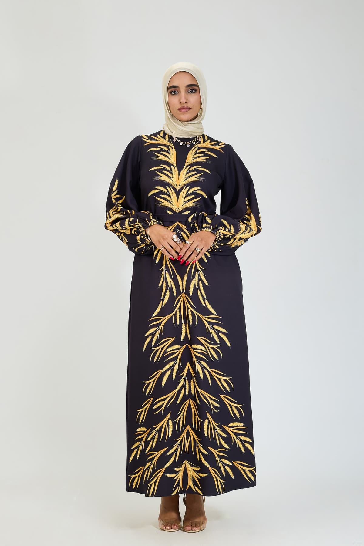 Close-up of flared sleeve with golden leaf design on black modesty dress.