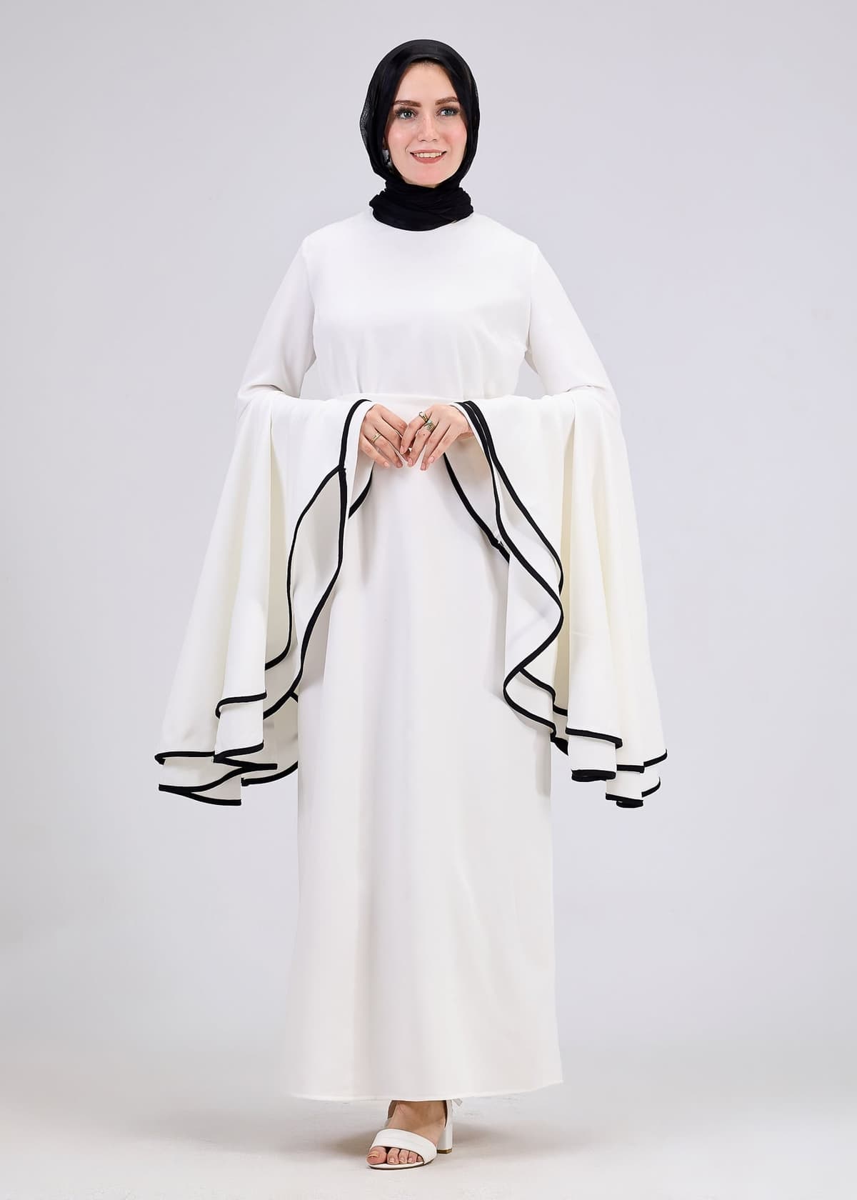 Model showcasing side view of white flared sleeve dress