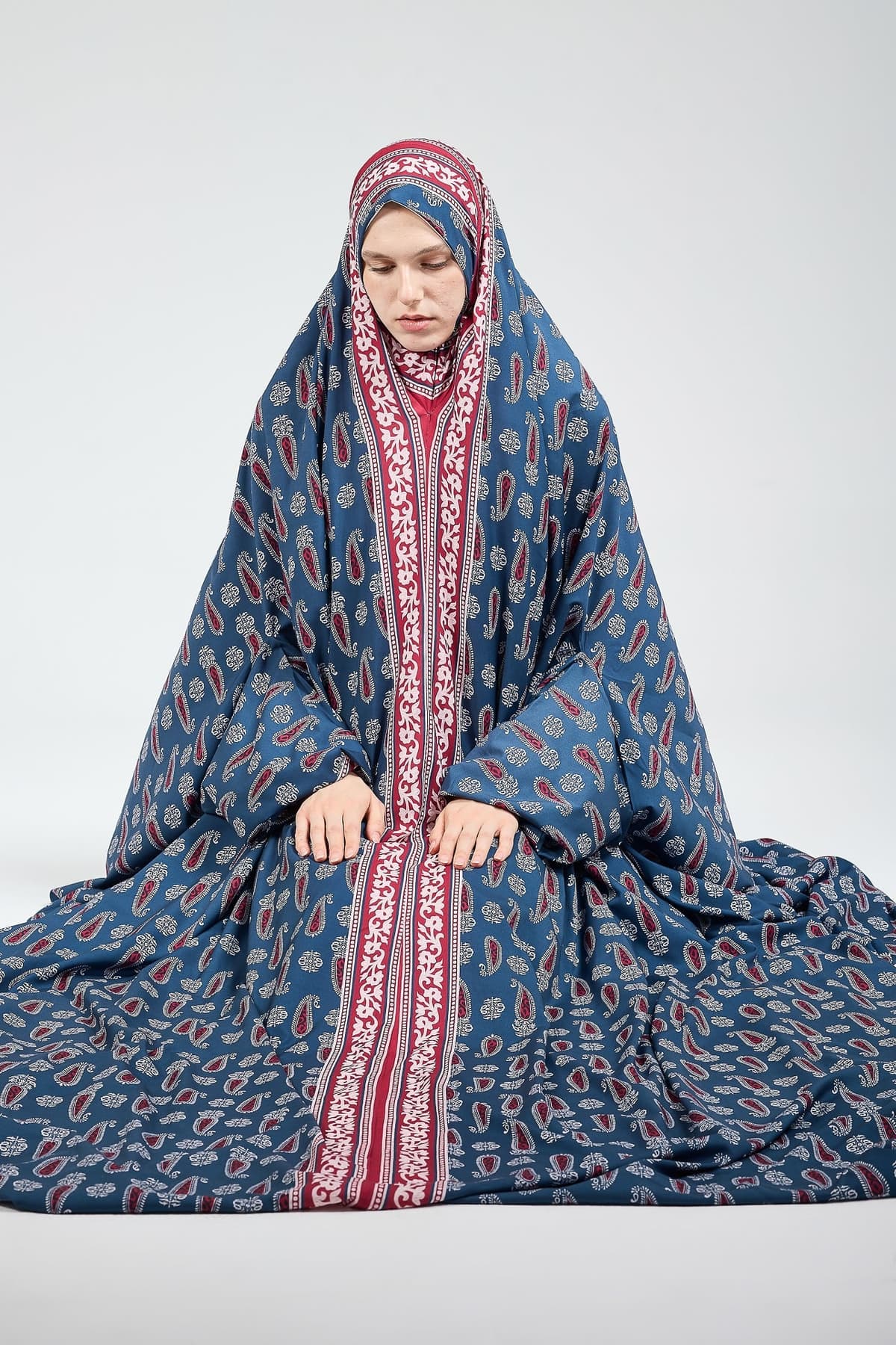Hands folded in satin prayer gown with intricate design.