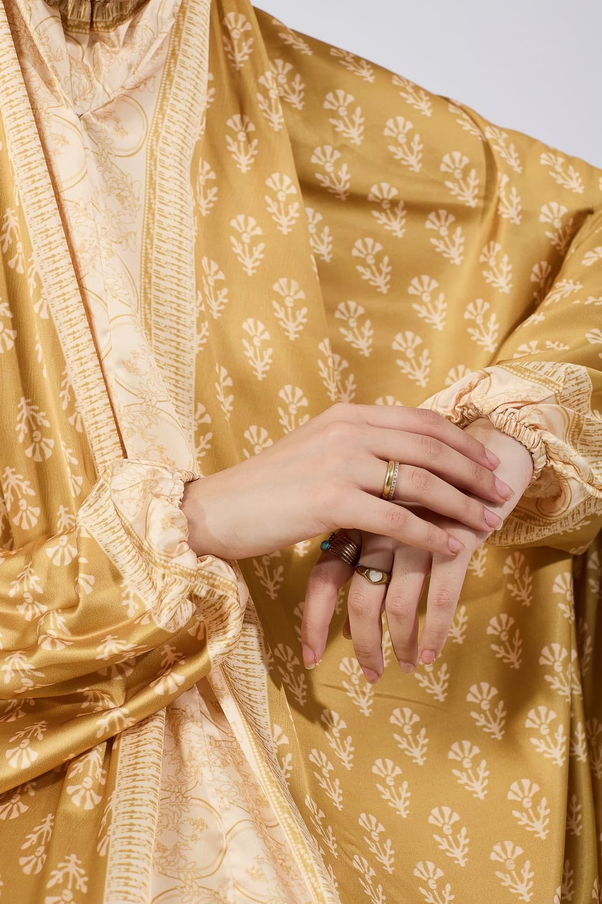 Side view of elegant golden satin prayer gown with floral accents